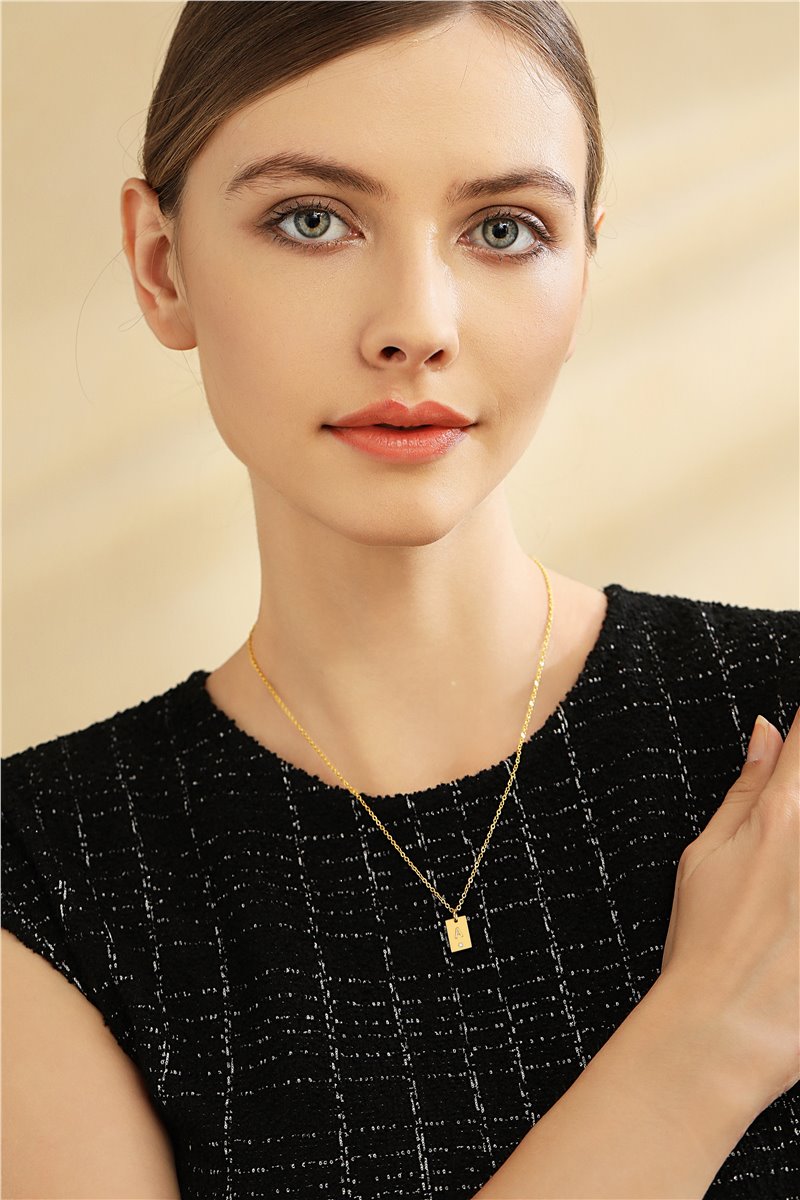 Model wearing gold initial necklace with black outfit